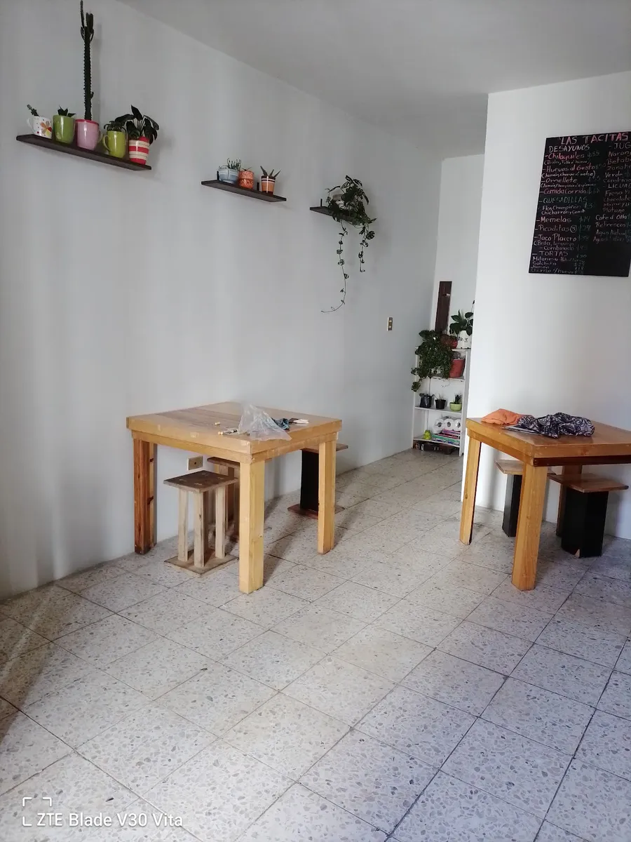 Nuestro local: mesas de madera, paredes blancas y el pizarrón del día