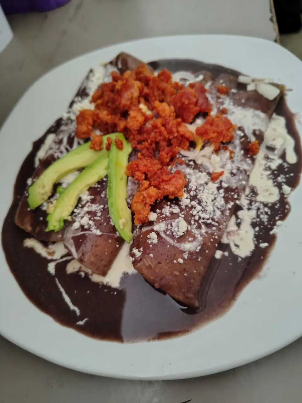 Enfrijoladas con chorizo, crema, queso y rebanadas de aguacate